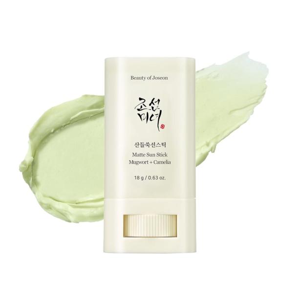 Ein „Beauty of Joseon“ Matte Sun Stick mit Beifuß und Kamelie neben einem grünen Abstrich.