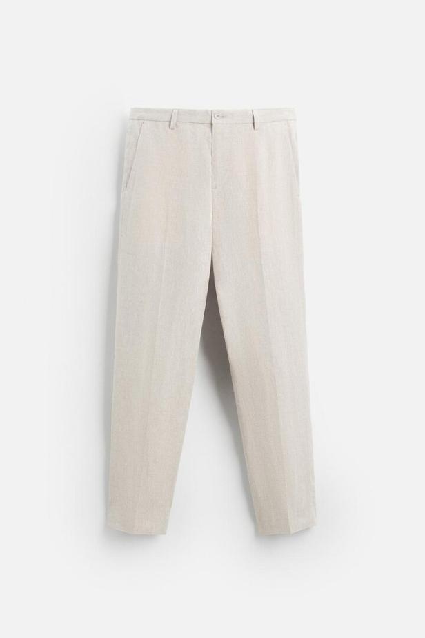 Eine hellbeige Leinenhose hängt vor einem weißen Hintergrund.