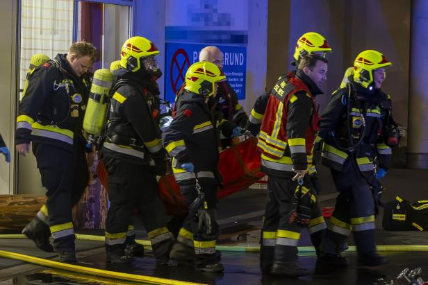 Mehrere Feuerwehrmänner tragen einen Mann im Tuch. Mehrere Feuerwehrmänner tragen einen Mann im Tuch.