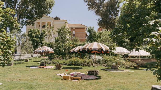 Ein Garten mit Sonnenschirmen und Picknickdecken in Borgo Pigneto.
