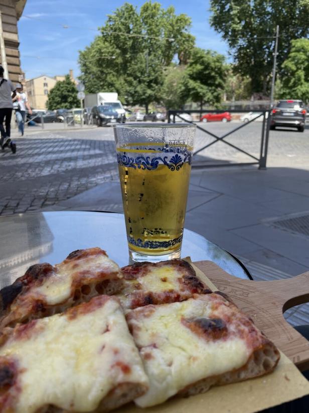 Ein Glas Bier und Pizza auf einem Tisch in Rom.