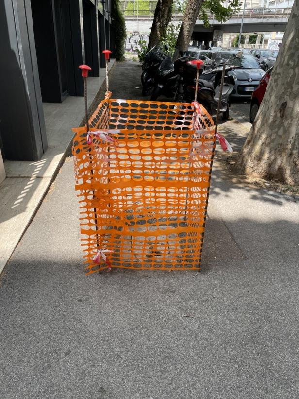 Ein orangefarbener Bauzaun steht auf einem Bürgersteig in Rom.