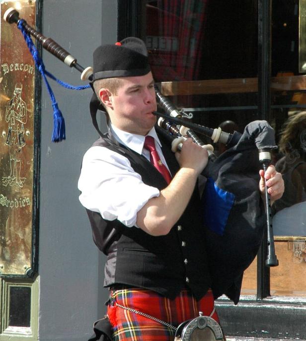 Ein Dudelsackspieler in traditioneller schottischer Kleidung spielt sein Instrument.