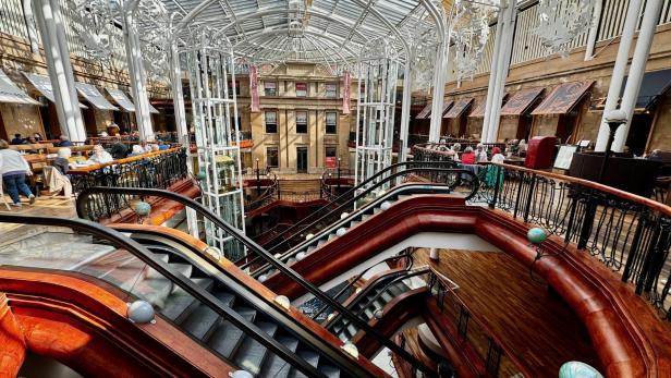 Blick in das Innere des Princes Square Einkaufszentrums in Glasgow mit Rolltreppen und Restaurants.
