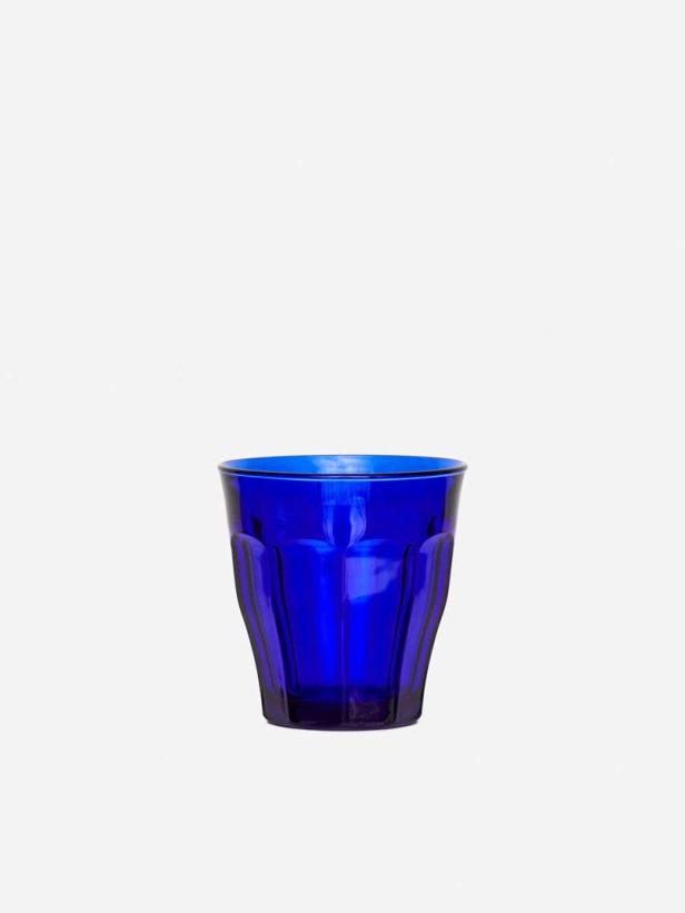 Ein blaues Trinkglas steht vor einem weißen Hintergrund.