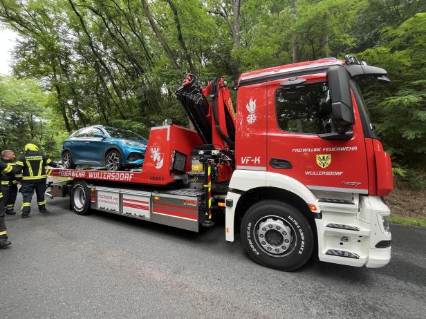 Ein blauer PKW wird von einem roten Feuerwehr-Abschleppwagen der Freiwilligen Feuerwehr Wullersdorf transportiert.