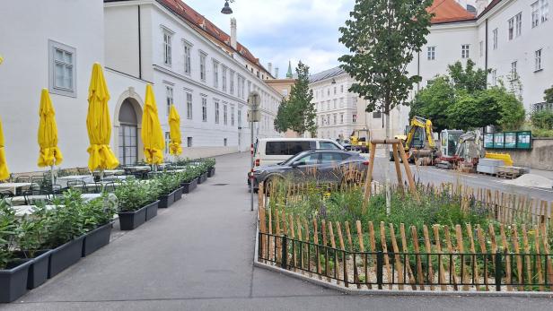 Eine Straßenszene in Wien mit Bauarbeiten und einem Straßencafé.