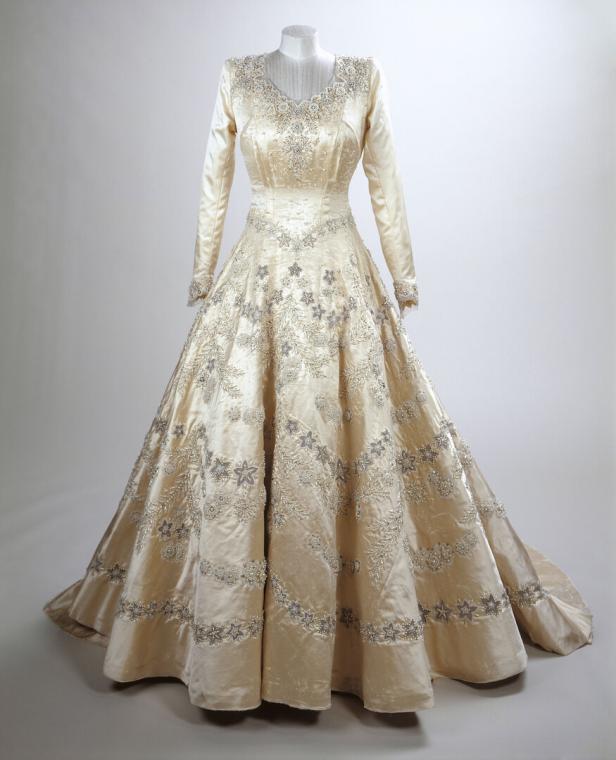 Ein cremefarbenes, langärmeliges Kleid mit floralen Stickereien, aus der Ausstellung „Queen Elizabeth II: Her Life in Style“.