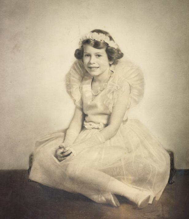 Queen Elizabeth II. in einem hellen Kleid mit Blumenkranz, Ausstellung Buckingham Palace 2026.