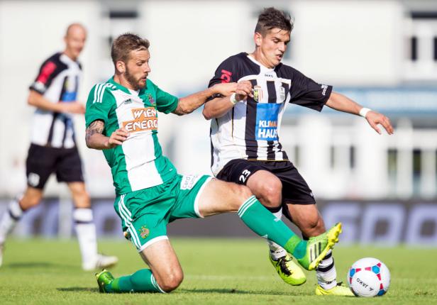 Zwei Fußballspieler kämpfen um den Ball auf dem Spielfeld.