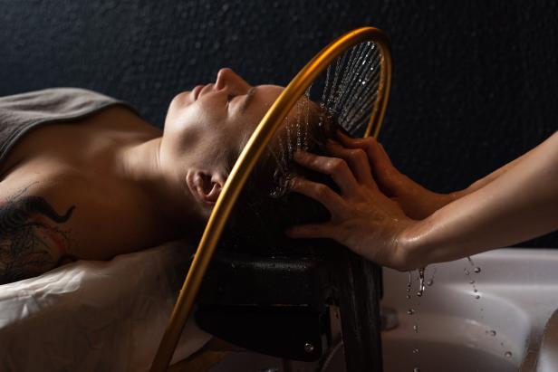 Ein Masseur massiert Kopf und Haare einer Frau in einem Spa-Salon.