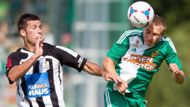 Zwei Fußballspieler kämpfen um den Ball während eines Spiels.
