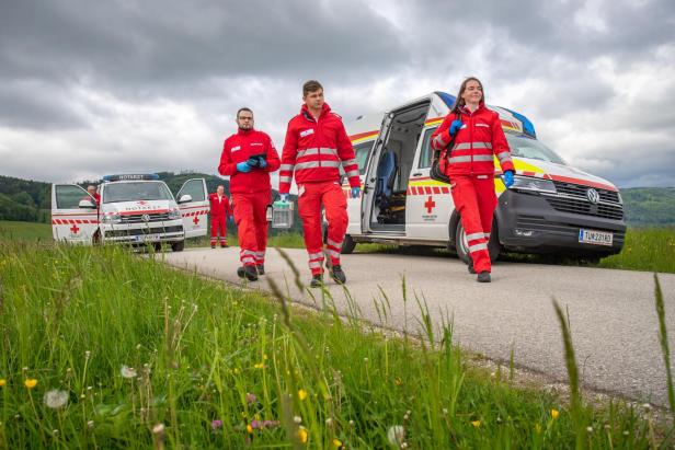 Drei Sanitäterinnen und Sanitäter vor Notarzteinsatzfahrzeugen