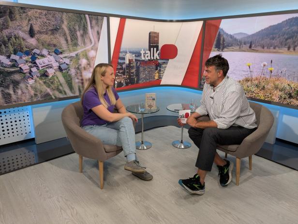 Eine Frau und ein Mann sitzen in einem Fernsehstudio und unterhalten sich.
