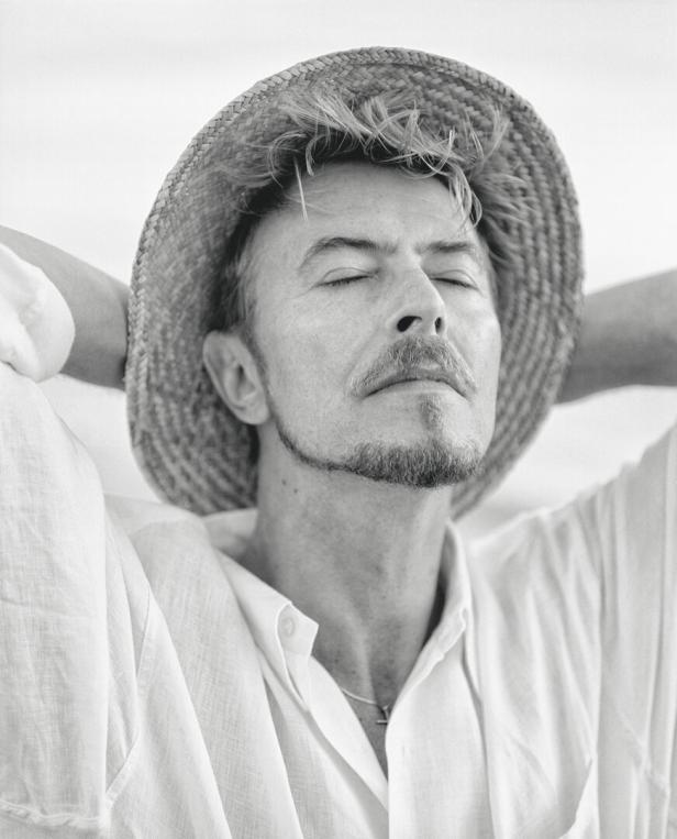 David Bowie entspannt mit geschlossenen Augen und einem Strohhut.