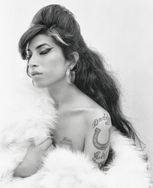 Schwarz-Weiß-Porträt von Amy Winehouse mit Pelzstola und Tattoos.