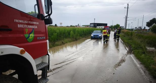 Ein Feuerwehrauto der Freiwilligen Feuerwehr Breitenwaida steht auf einer überfluteten Straße.