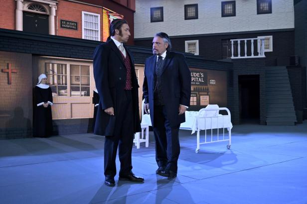 Zwei Männer in Anzügen stehen vor dem Bühnenbild von „Jekyll & Hyde“.