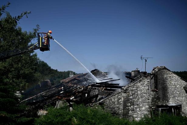 TOPSHOT-FRANCE-FIRE Ein Feuerwehrmann löscht ein brennendes Haus mit einem Wasserstrahl.