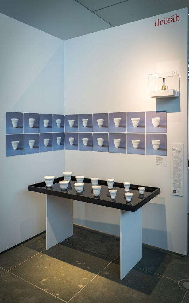 Eine Kunstinstallation mit weißen Bechern auf einem Tisch und an der Wand.