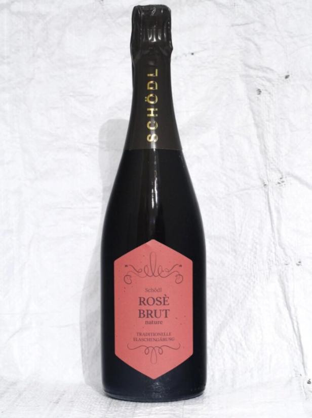 Eine Flasche „Schödl Rosé Brut nature“ Sekt steht auf einem weißen Tuch.