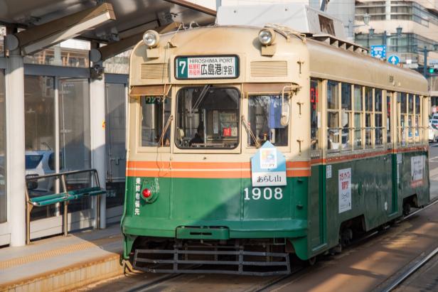 Eine grüne und beige Straßenbahn der Linie 7 am Hiroshima Port.