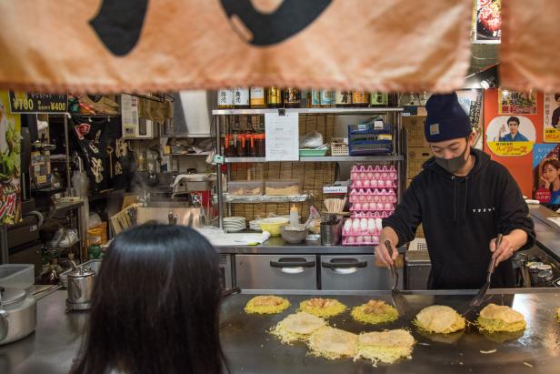 Ein Koch bereitet Okonomiyaki in einem japanischen Restaurant zu.