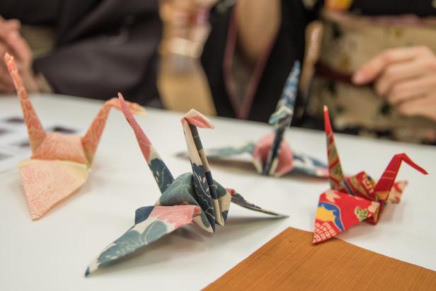 Mehrere bunte Origami-Kraniche stehen auf einem Tisch.