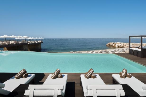 Ein Poolbereich im Purobeach Portopiccolo mit Blick auf das Meer.