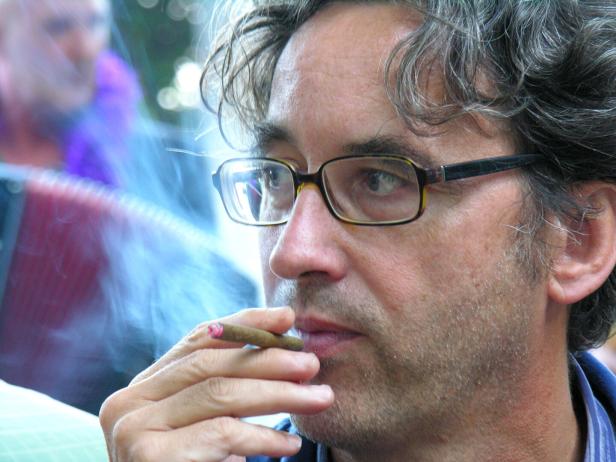 Ein Mann mit Brille raucht eine Zigarre.