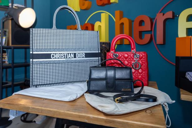 Eine Christian Dior-Tasche, eine rote Handtasche und eine schwarze Jacquemus-Tasche auf einem Tisch.