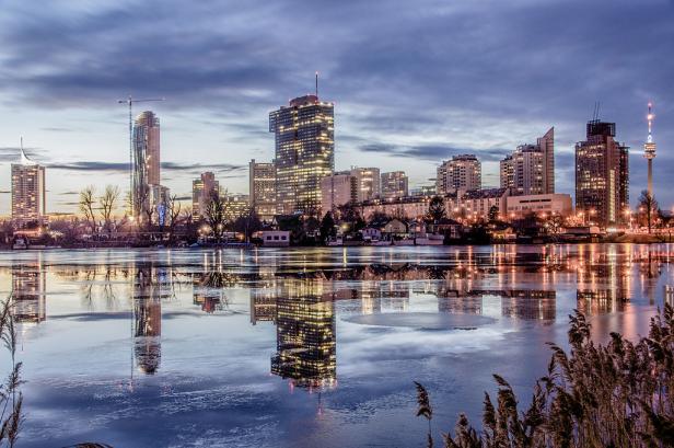 Die Skyline von Wien spiegelt sich im Wasser bei Dämmerung.
