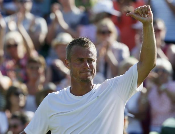 Ein Tennisspieler jubelt mit erhobenem Arm vor einer Zuschauermenge.