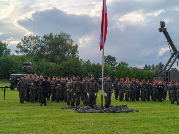 Soldaten stehen bei der Angelobung in Großharras vor der österreichischen Flagge.