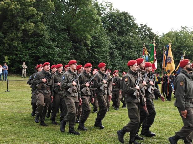 Soldaten in Uniformen und roten Baretts marschieren bei der Angelobung in Großharras.