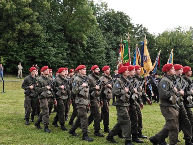 Soldaten in Uniformen und roten Baretten marschieren bei der Angelobung in Großharras.