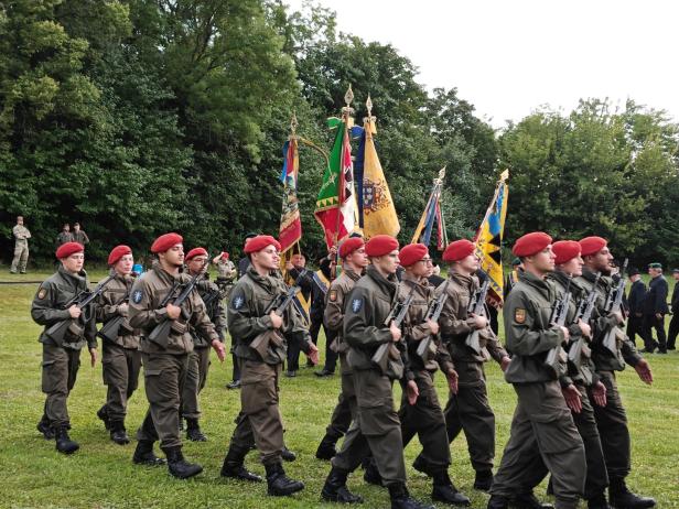 Soldaten in Uniform und roten Baretts marschieren bei der Angelobung in Großharras.
