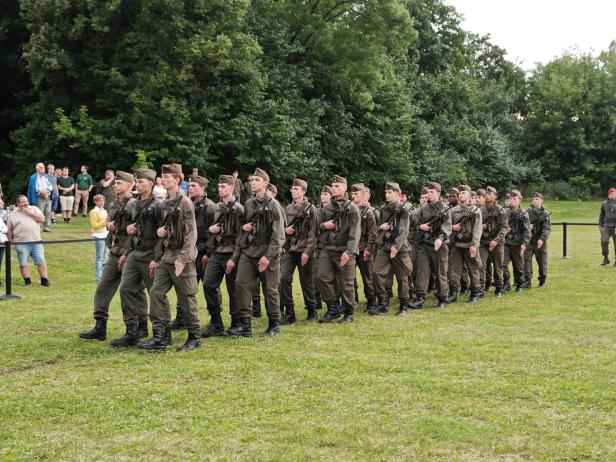 Eine Reihe von Soldaten marschiert auf einer Wiese in Großharras.