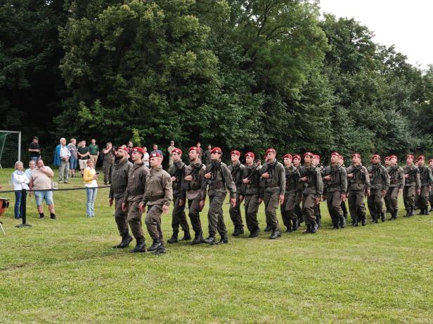 Soldaten in Uniform und mit roten Baretts marschieren bei der Angelobung in Großharras.