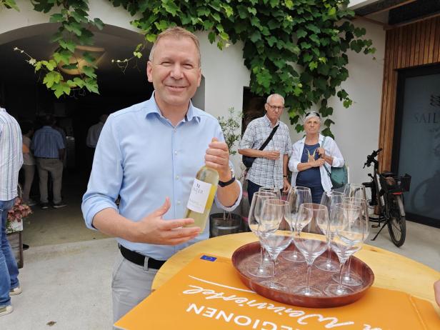 Ein Mann präsentiert eine Flasche Sailer Weinviertel bei einer Weinprobe.