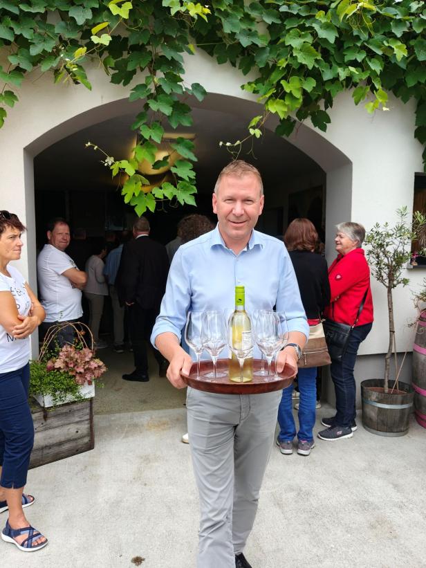 Ein Mann serviert Wein auf einem Tablett bei einer „Sommergenusstour Weinviertel“.