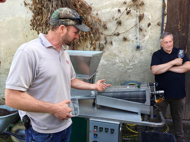 Zwei Männer stehen neben einer Weinpresse im Weinviertel.