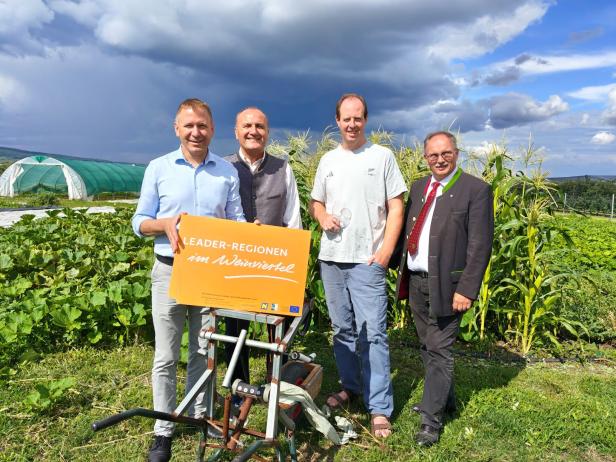 Vier Männer stehen vor einem Feld und halten ein Schild mit der Aufschrift „LEADER-Regionen im Weinviertel“.