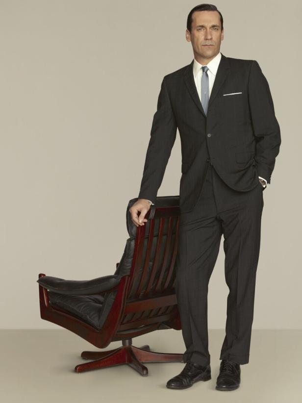 Jon Hamm, als Don Draper in „Mad Men“, posiert neben einem Bürostuhl.