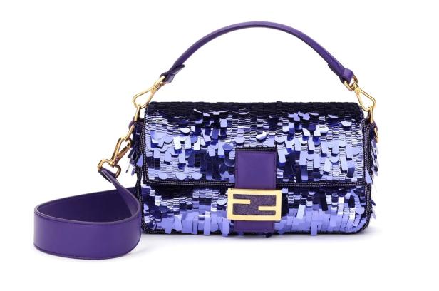 Eine lila Fendi Baguette-Tasche, verziert mit Pailletten, liegt auf einem weißen Hintergrund.