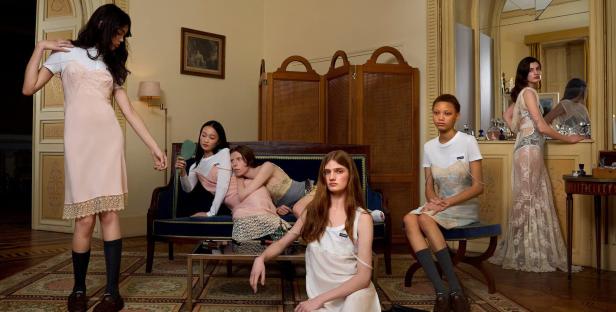 Mehrere junge Frauen posieren in Kleidern in einem eleganten Interieur.