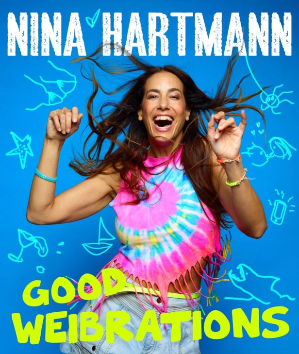 Nina Hartmann, gut gelaunt und mit flatterndem Haar, vor blauem Hintergrund mit Kritzeleien.
