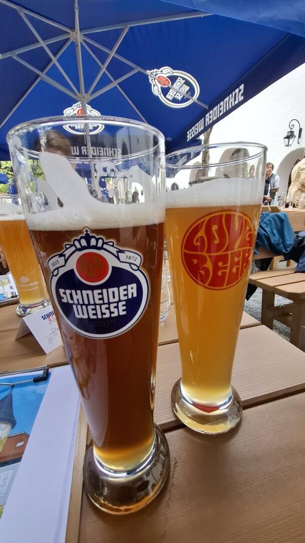Zwei Gläser Bier der Marken Schneider Weisse und Aecht Schlenkerla auf einem Tisch.