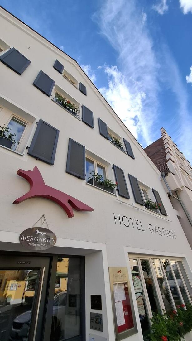 Das Hotel Gasthof „Fuchsbräu“ mit Biergarten unter blauem Himmel.