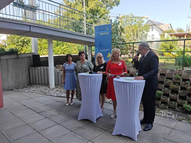 Eine Gruppe von Personen steht bei einer Veranstaltung im Freien vor einem Banner der Landesgesundheitsagentur.
